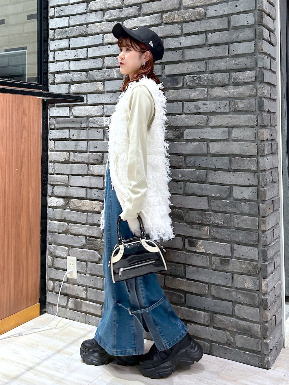 イエロー系のTシャツ/カットソー、ブラック系のショルダーバッグ、ブルー系のデニムスカートを着用したレディースの秋コーディネートの3枚目の写真