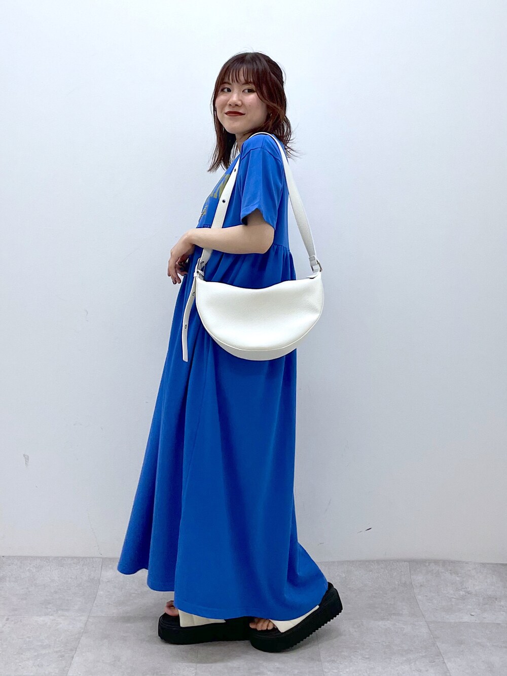 ブルー系のワンピース、ホワイト系のショルダーバッグ、ホワイト系のサンダルを着用したレディースの春コーディネートの3枚目の写真