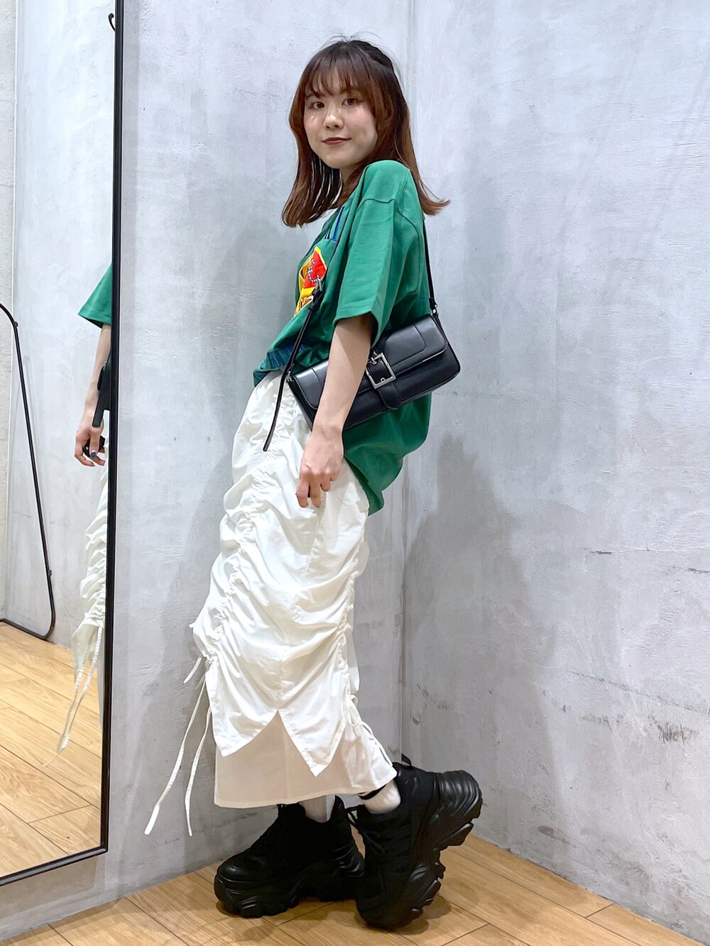 ブラック系のスニーカー、ホワイト系のスカート、ブラック系のハンドバッグを着用したレディースの春コーディネートの3枚目の写真