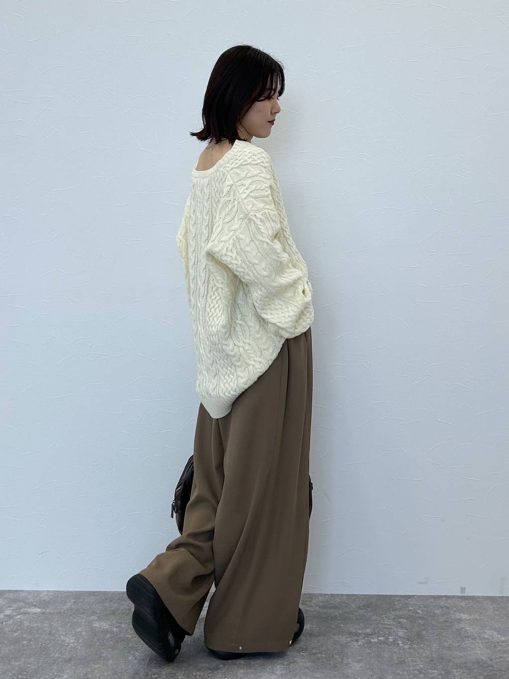 ブラウン系のボストンバッグ、ホワイト系のニット/セーター、ベージュ系のスラックスを着用したレディースの冬コーディネートの5枚目の写真