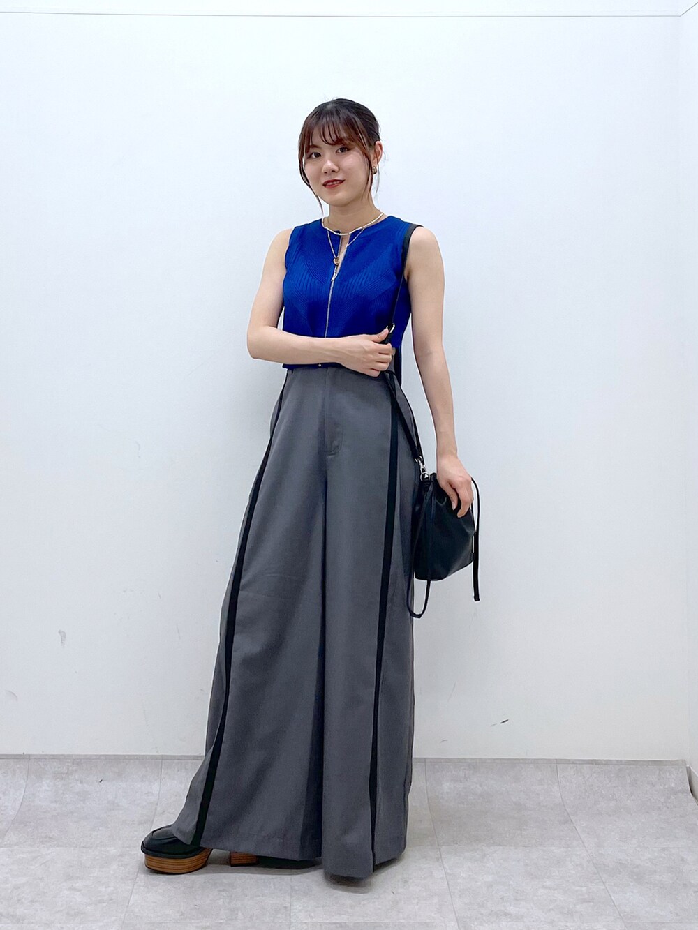 ブルー系のタンクトップ、グレー系のスラックス、ブラック系のローファーを着用したレディースの夏コーディネートの2枚目の写真