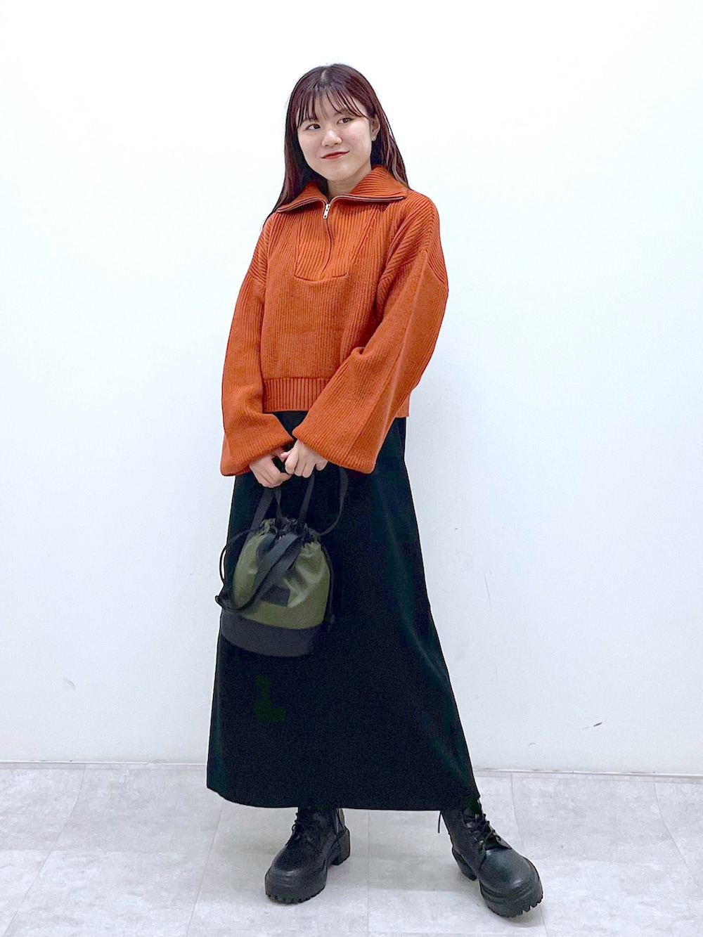ブラック系のブーツ、ブラック系のワンピース、オレンジ系のニット/セーターを着用したレディースの秋コーディネートの2枚目の写真