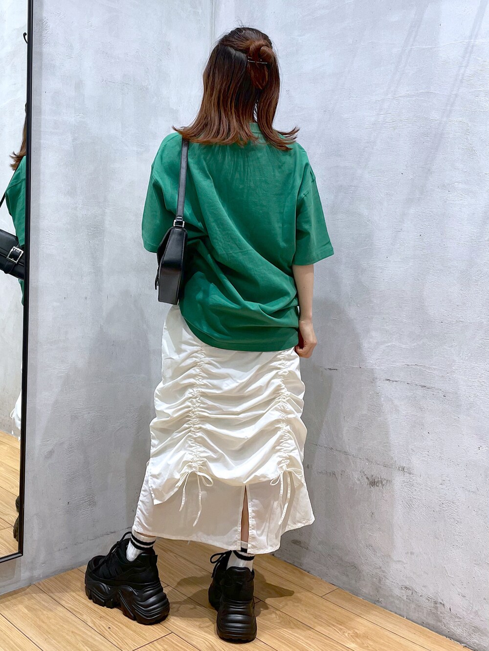 ブラック系のスニーカー、ホワイト系のスカート、ブラック系のハンドバッグを着用したレディースの春コーディネートの5枚目の写真