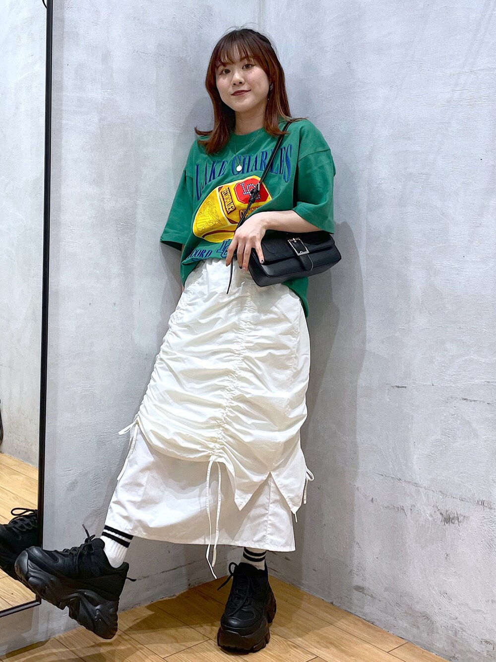 ブラック系のスニーカー、ホワイト系のスカート、ブラック系のハンドバッグを着用したレディースの春コーディネートの2枚目の写真