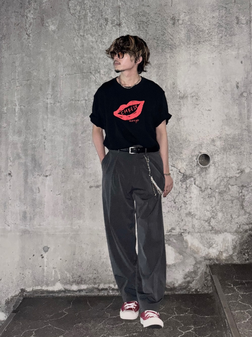 レッド系のスニーカー、ブラック系のTシャツ/カットソー、グレー系のスラックスを着用したメンズの夏コーディネートの3枚目の写真