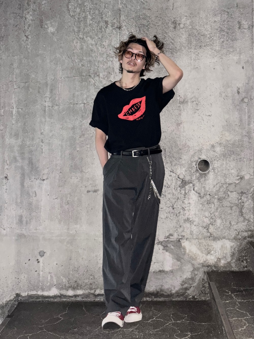 レッド系のスニーカー、ブラック系のTシャツ/カットソー、グレー系のスラックスを着用したメンズの夏コーディネートの2枚目の写真