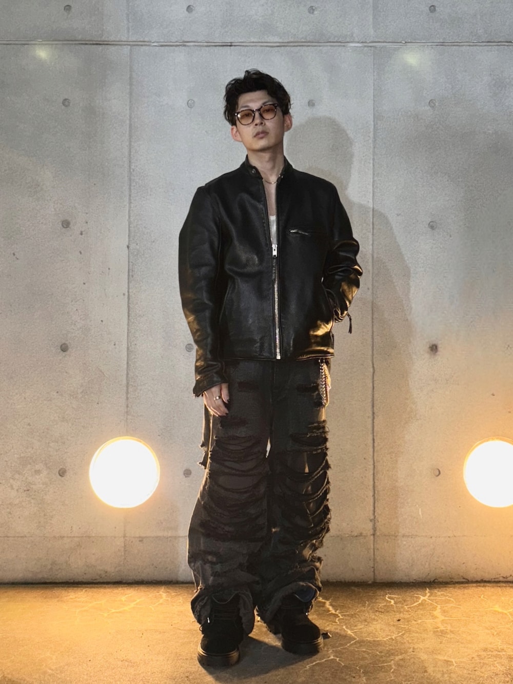 ブラック系のブーツ、ブラック系のデニムパンツ、ホワイト系のタンクトップを着用したメンズの秋コーディネートの3枚目の写真