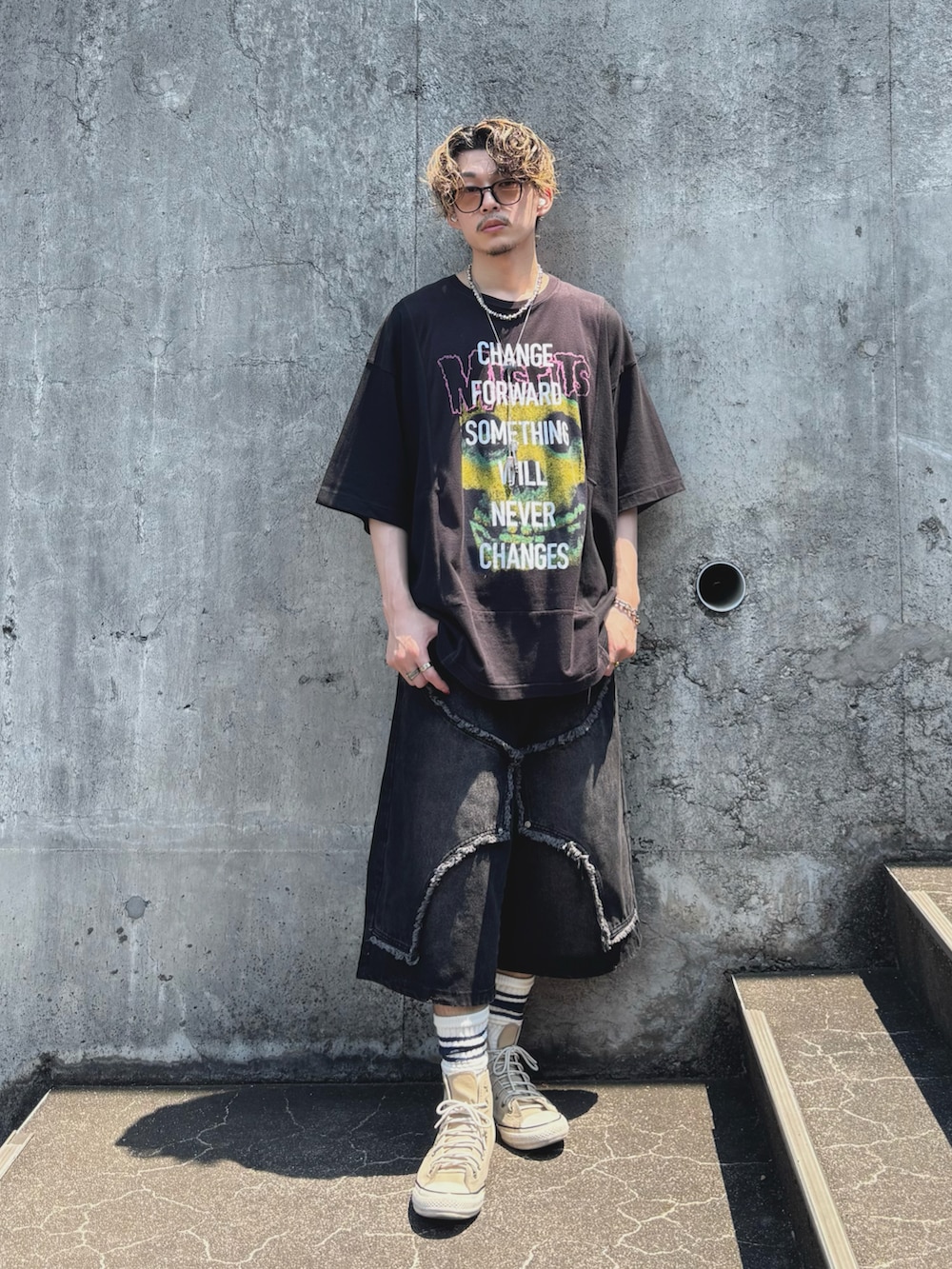 ブラック系のデニムパンツ、ベージュ系のスニーカー、ブラック系のTシャツ/カットソーを着用したメンズの夏コーディネートの3枚目の写真