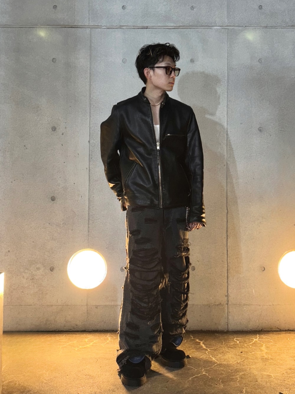 ブラック系のブーツ、ブラック系のデニムパンツ、ホワイト系のタンクトップを着用したメンズの秋コーディネートの2枚目の写真