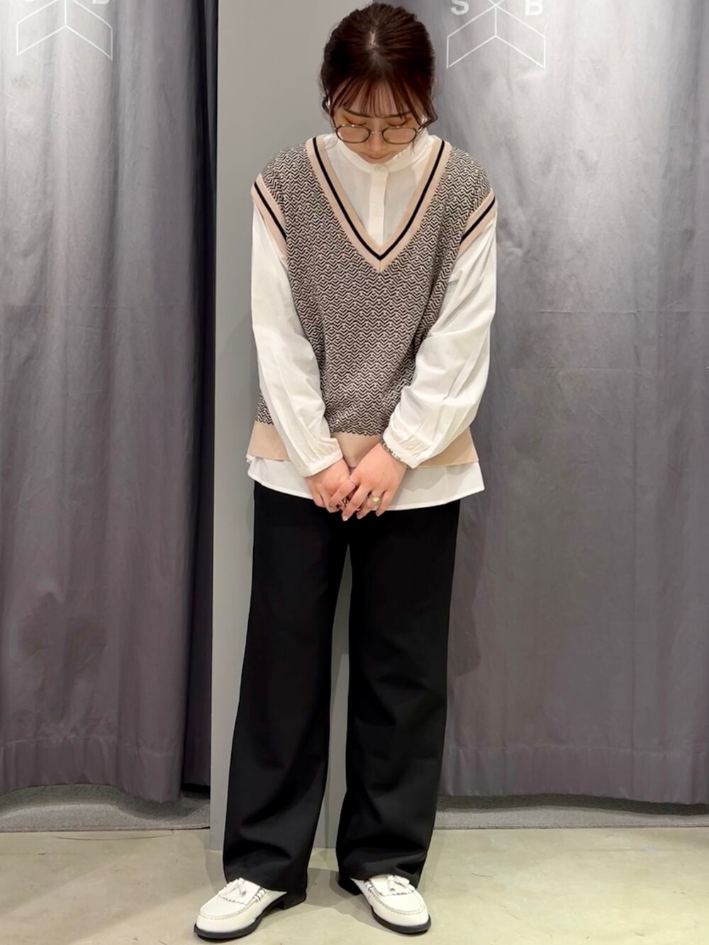 ホワイト系のシャツ/ブラウス、ベージュ系のベスト、ブラック系のスラックスを着用したレディースの春コーディネートの2枚目の写真