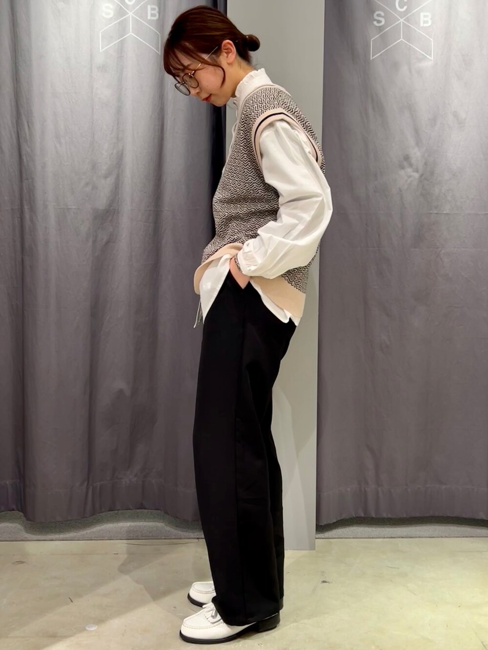 ホワイト系のシャツ/ブラウス、ベージュ系のベスト、ブラック系のスラックスを着用したレディースの春コーディネートの3枚目の写真