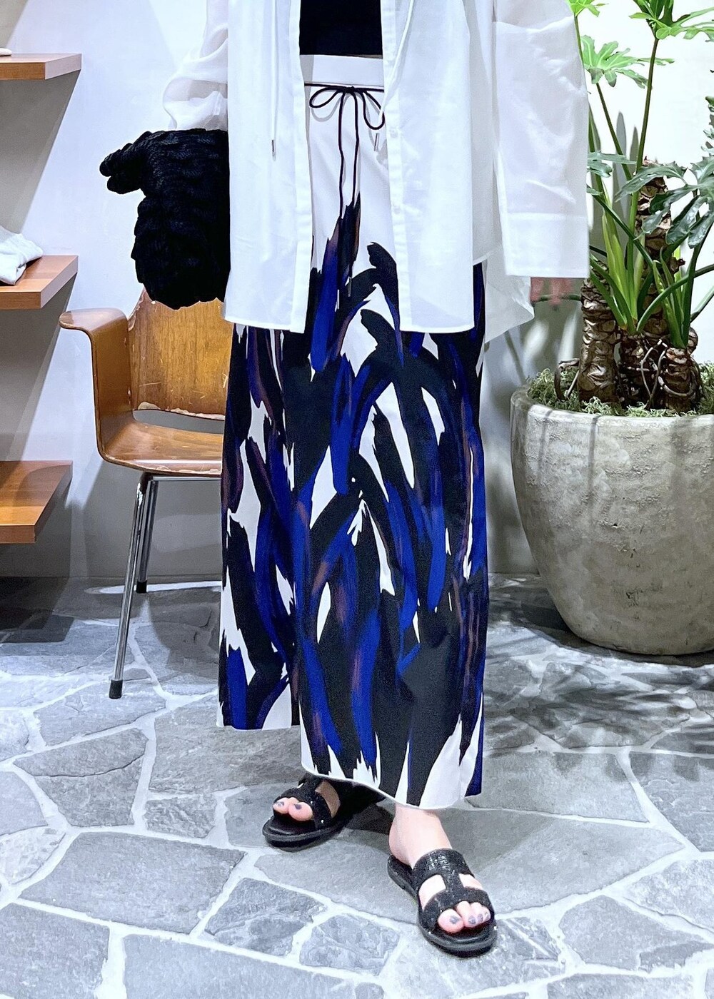 ブラック系のハンドバッグ、ブラック系のサンダル、ホワイト系のシャツ/ブラウスを着用したレディースの春コーディネートの5枚目の写真