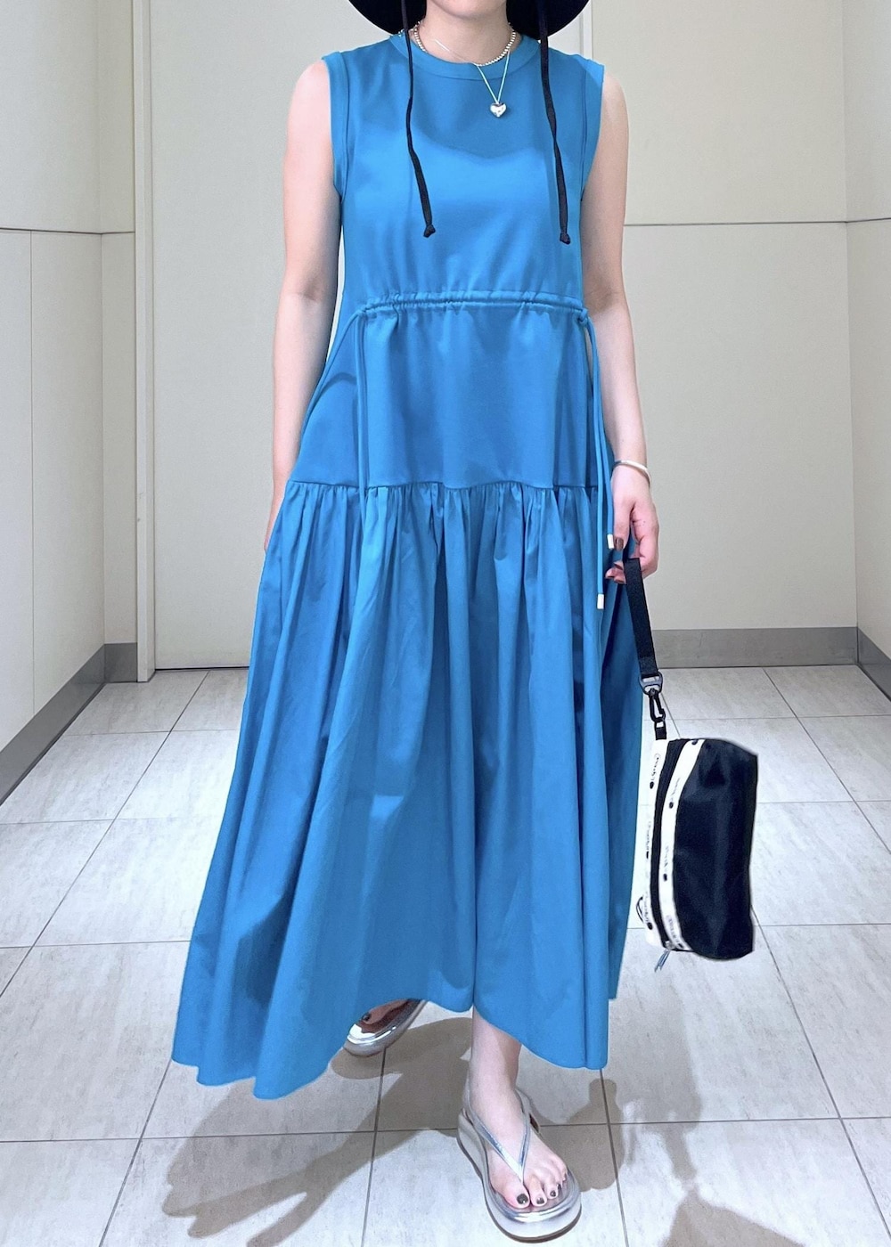 シルバー系のサンダル、ブルー系のワンピース、ブラック系のポーチを着用したレディースの夏コーディネートの5枚目の写真