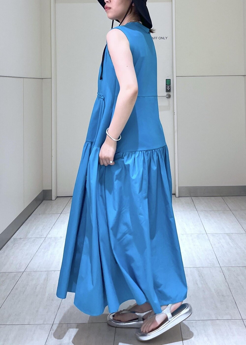 シルバー系のサンダル、ブルー系のワンピース、ブラック系のポーチを着用したレディースの夏コーディネートの6枚目の写真