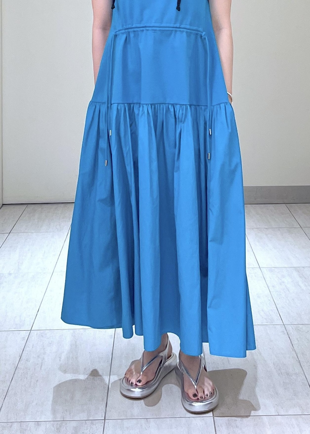 シルバー系のサンダル、ブルー系のワンピース、ブラック系のポーチを着用したレディースの夏コーディネートの4枚目の写真