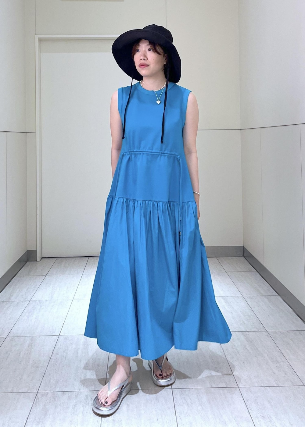 シルバー系のサンダル、ブルー系のワンピース、ブラック系のポーチを着用したレディースの夏コーディネートの3枚目の写真