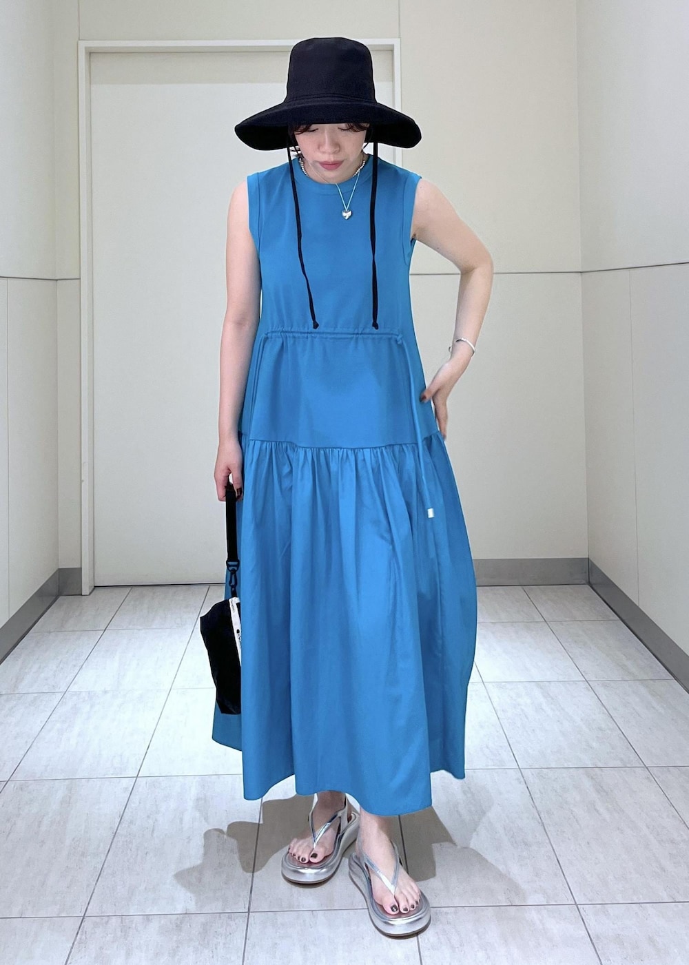 シルバー系のサンダル、ブルー系のワンピース、ブラック系のポーチを着用したレディースの夏コーディネートの2枚目の写真