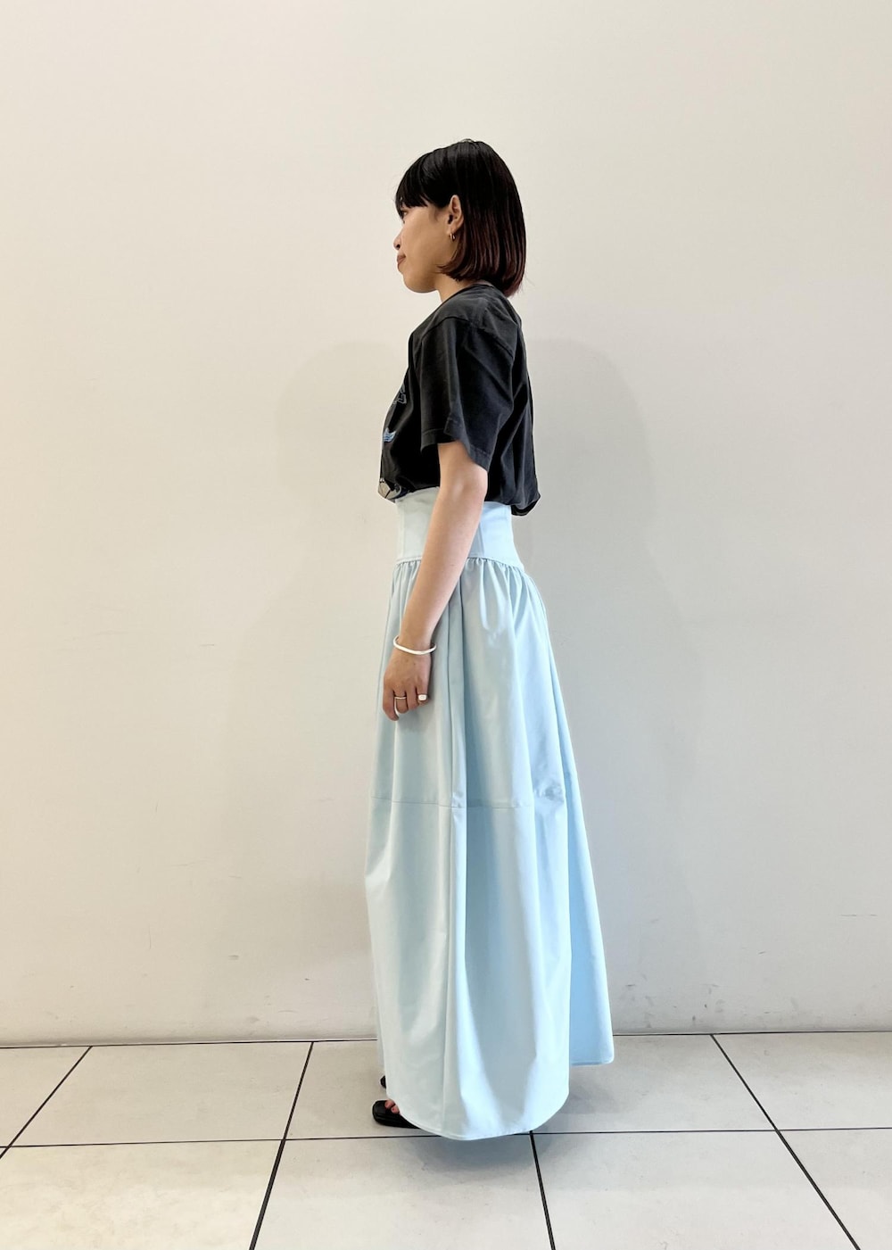 ブルー系のスカート、ブラック系のサンダル、ブラック系のショルダーバッグを着用したレディースの夏コーディネートの2枚目の写真