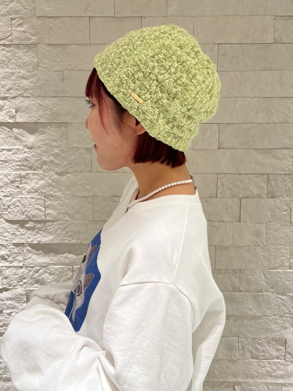 ホワイト系のスウェット、グレー系のスカート、グリーン系のニットキャップ/ビーニーを着用したレディースの冬コーディネートの3枚目の写真