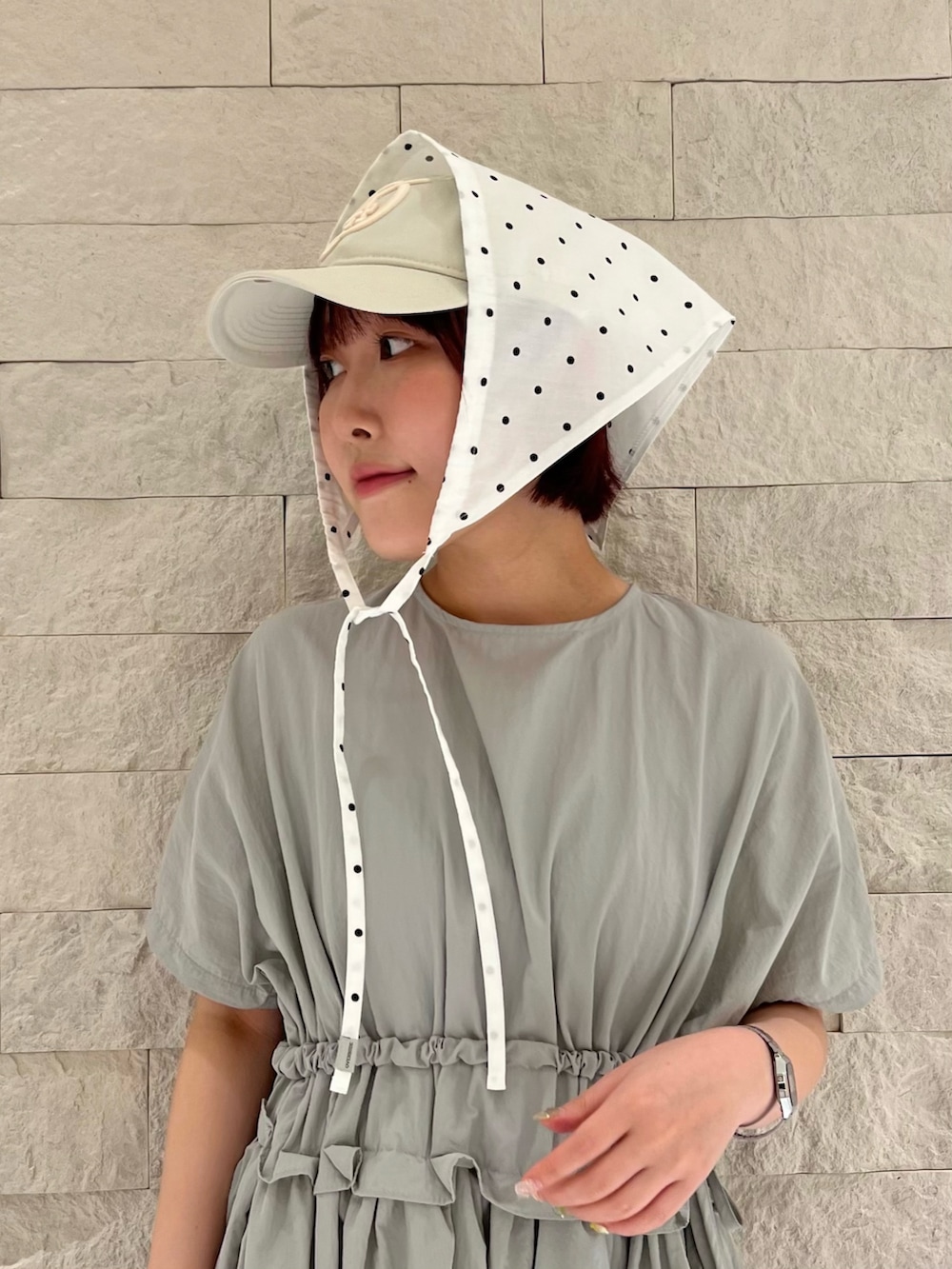 グレー系のスニーカー、ホワイト系のヘアバンド、ベージュ系のキャップを着用したレディースの夏コーディネートの2枚目の写真