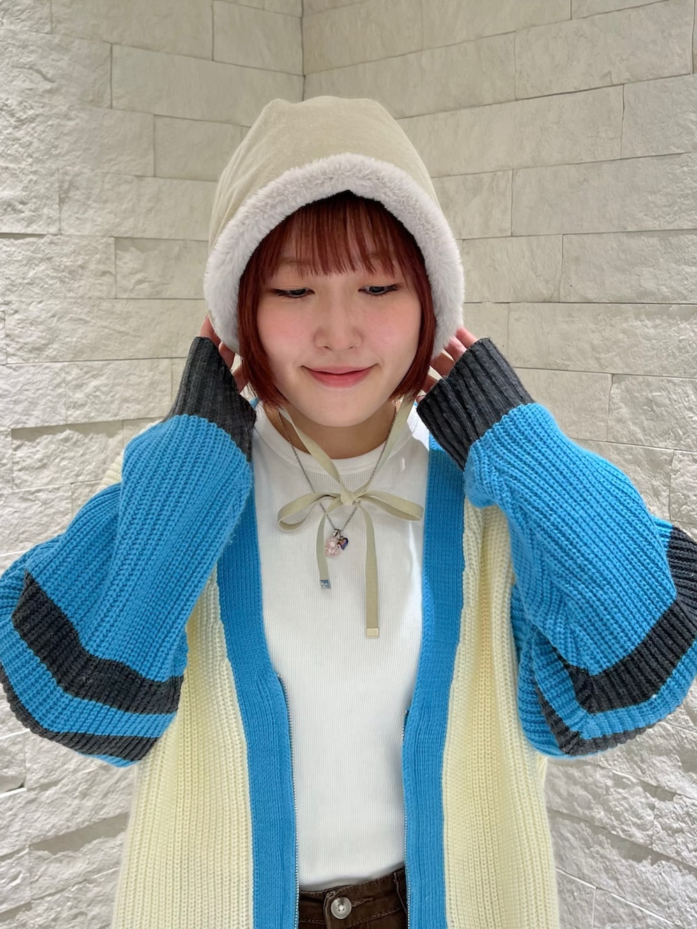 ホワイト系のカーディガン/ボレロ、ブルー系のスニーカー、ホワイト系のハットを着用したレディースの冬コーディネートの2枚目の写真