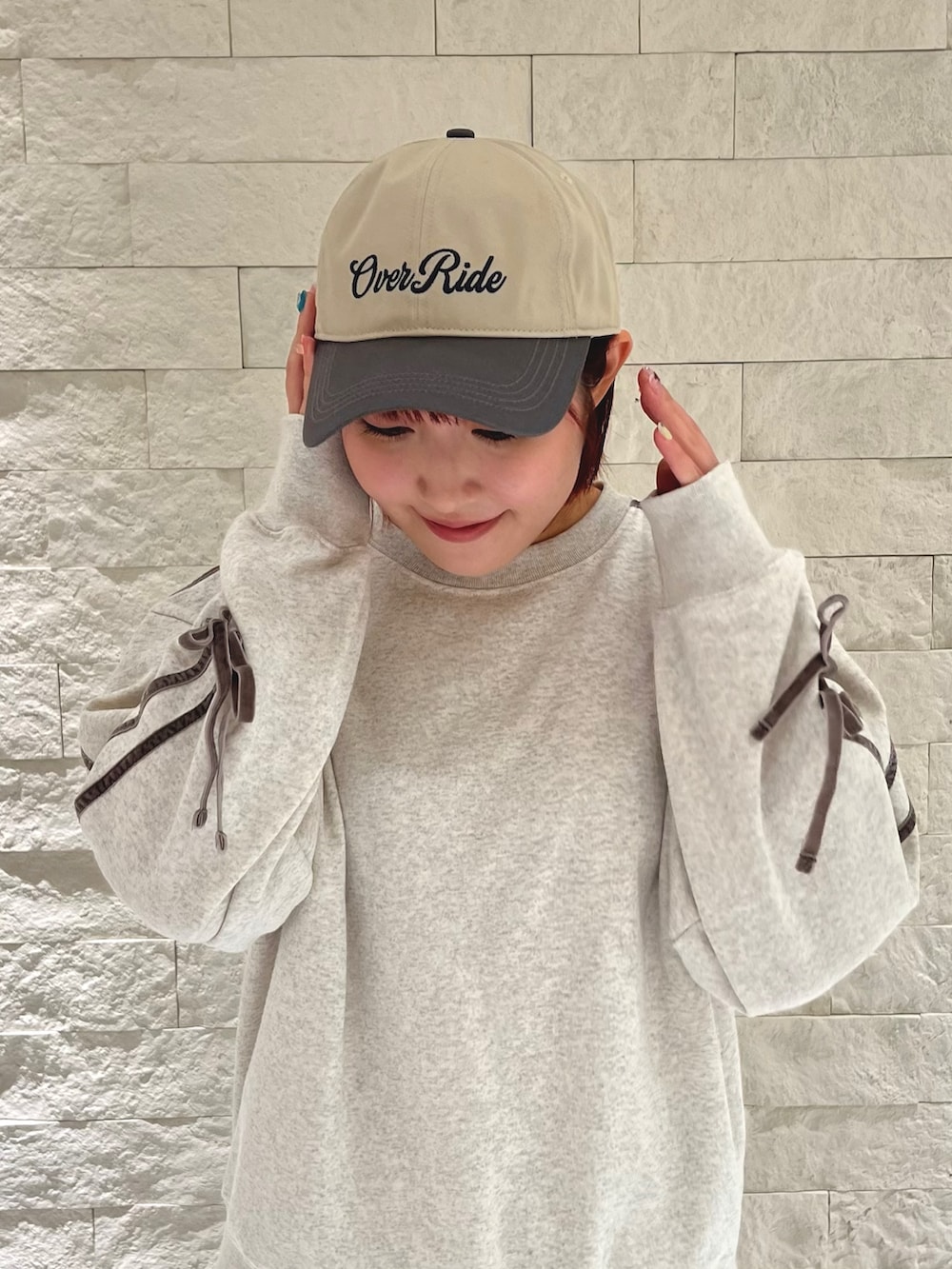 ブルー系のスニーカー、グレー系のスウェット、ベージュ系のキャップを着用したレディースの冬コーディネートの2枚目の写真