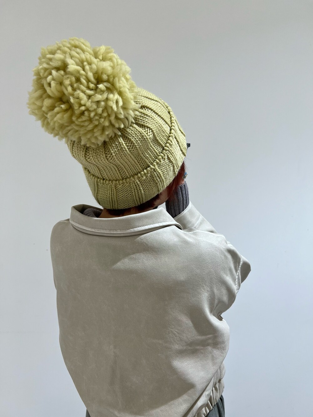 イエロー系のニットキャップ/ビーニーを着用したレディースの冬コーディネートの3枚目の写真