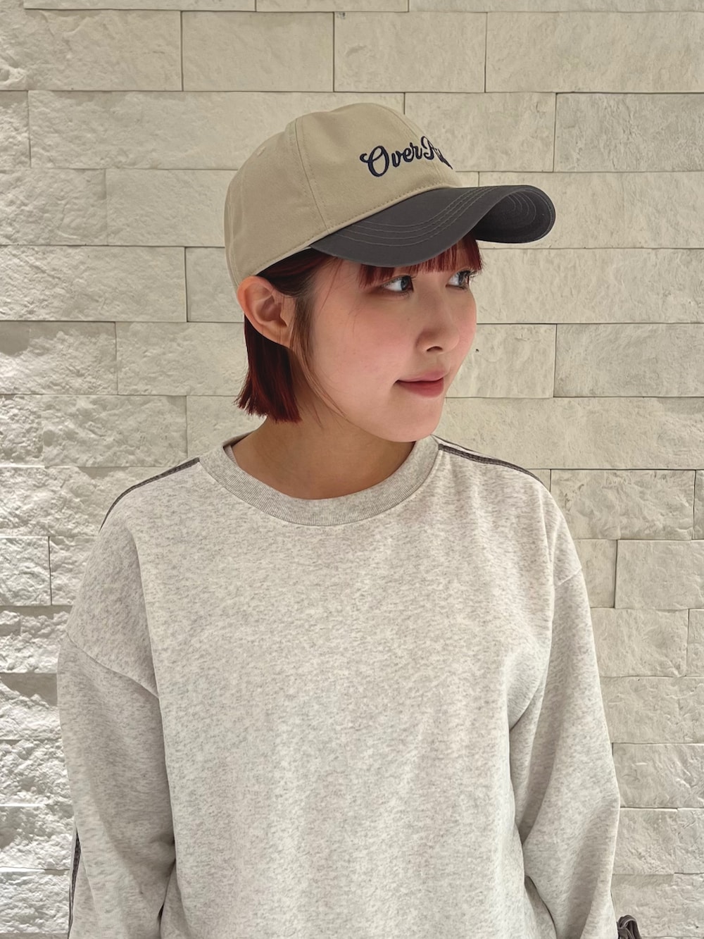 ブルー系のスニーカー、グレー系のスウェット、ベージュ系のキャップを着用したレディースの冬コーディネートの3枚目の写真