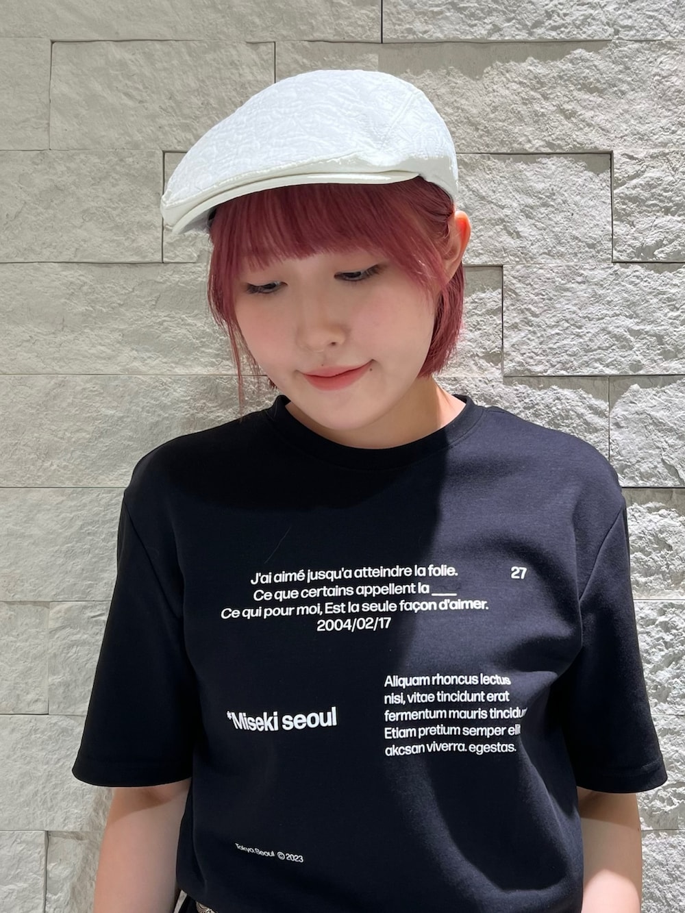 グレー系のスラックス、ブラック系のスニーカー、ホワイト系のハンチング/ベレー帽を着用したレディースの夏コーディネートの2枚目の写真