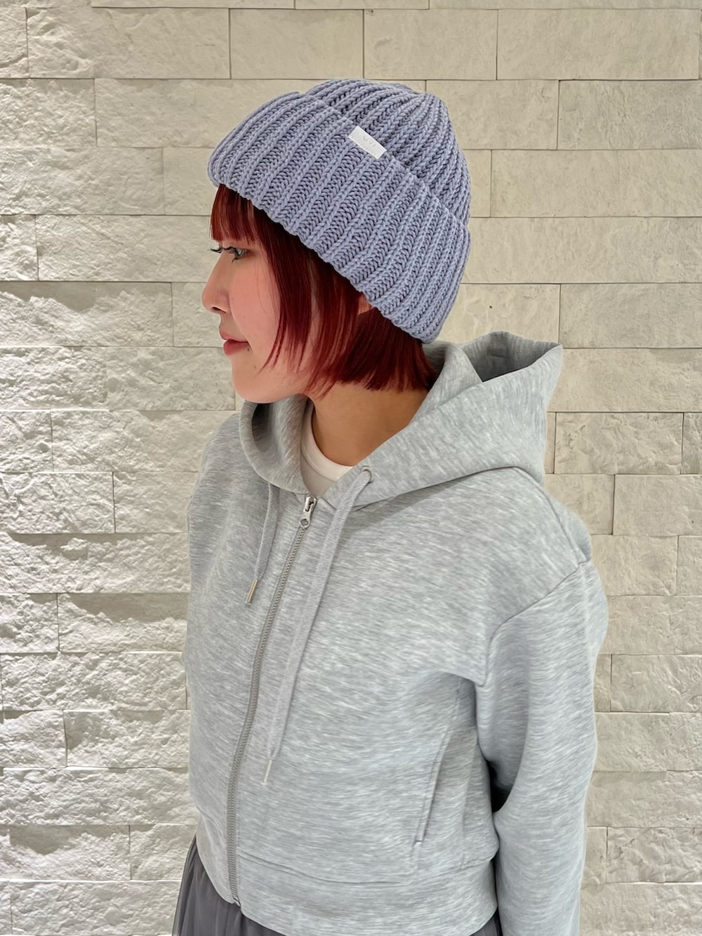 グレー系のスカート、グレー系のパーカー、ブルー系のニットキャップ/ビーニーを着用したレディースの冬コーディネートの2枚目の写真