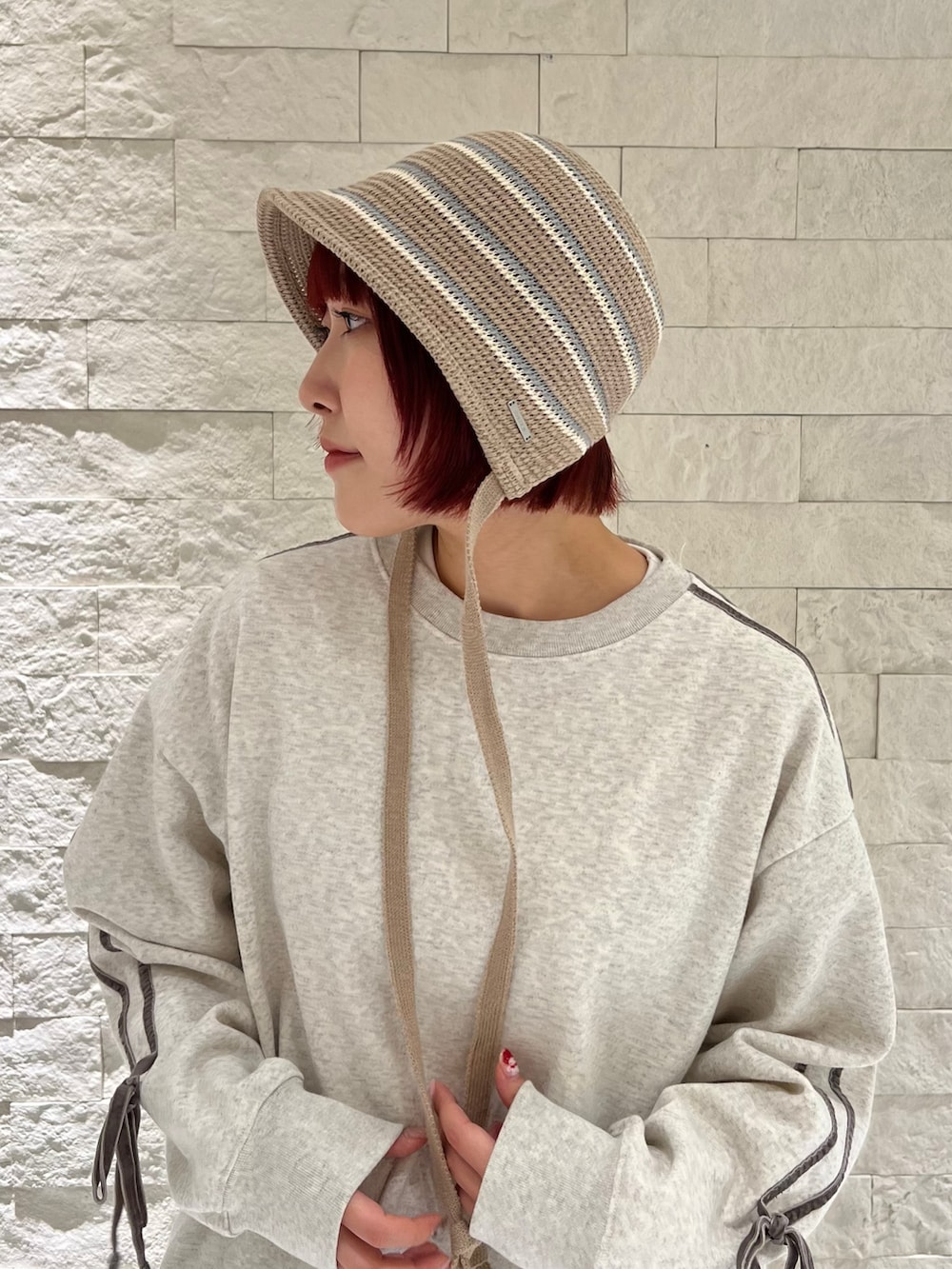 ブルー系のスニーカー、グレー系のスウェット、ブラウン系のハットを着用したレディースの冬コーディネートの2枚目の写真