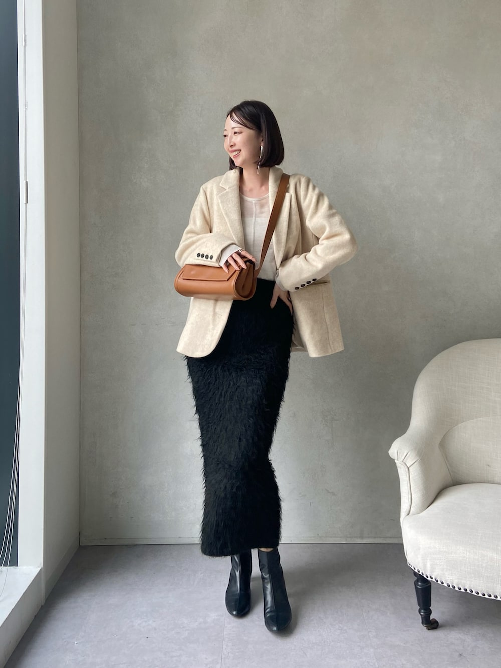 ベージュ系のテーラードジャケット、ブラック系のスカート、ベージュ系のショルダーバッグを着用したレディースの秋コーディネートの2枚目の写真