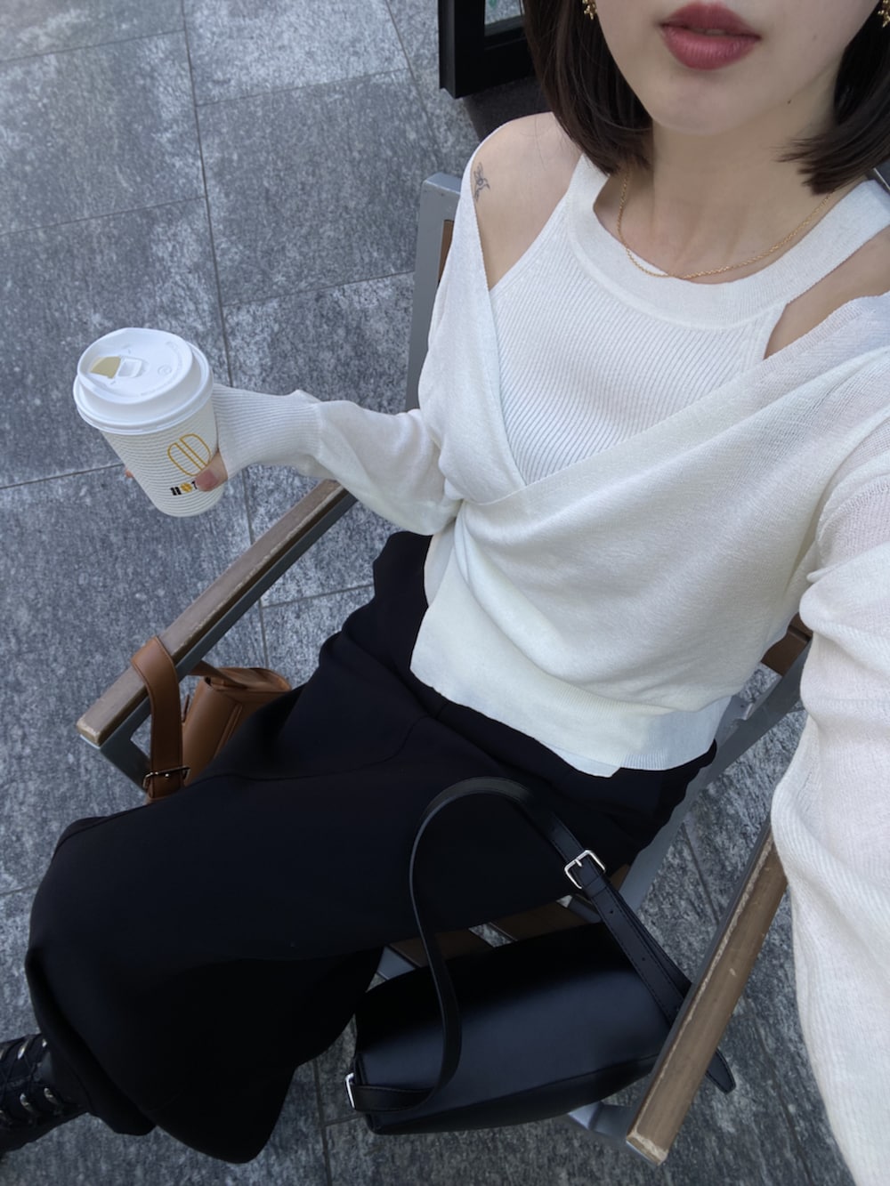 ブラック系のスカート、ベージュ系のショルダーバッグ、ホワイト系のカーディガン/ボレロを着用したレディースの春コーディネートの3枚目の写真