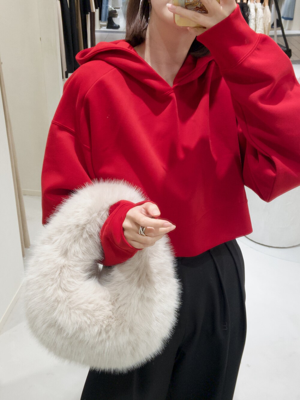 レッド系のパーカー、ホワイト系のハンドバッグ、ブラック系のその他パンツを着用したレディースの秋コーディネートの4枚目の写真