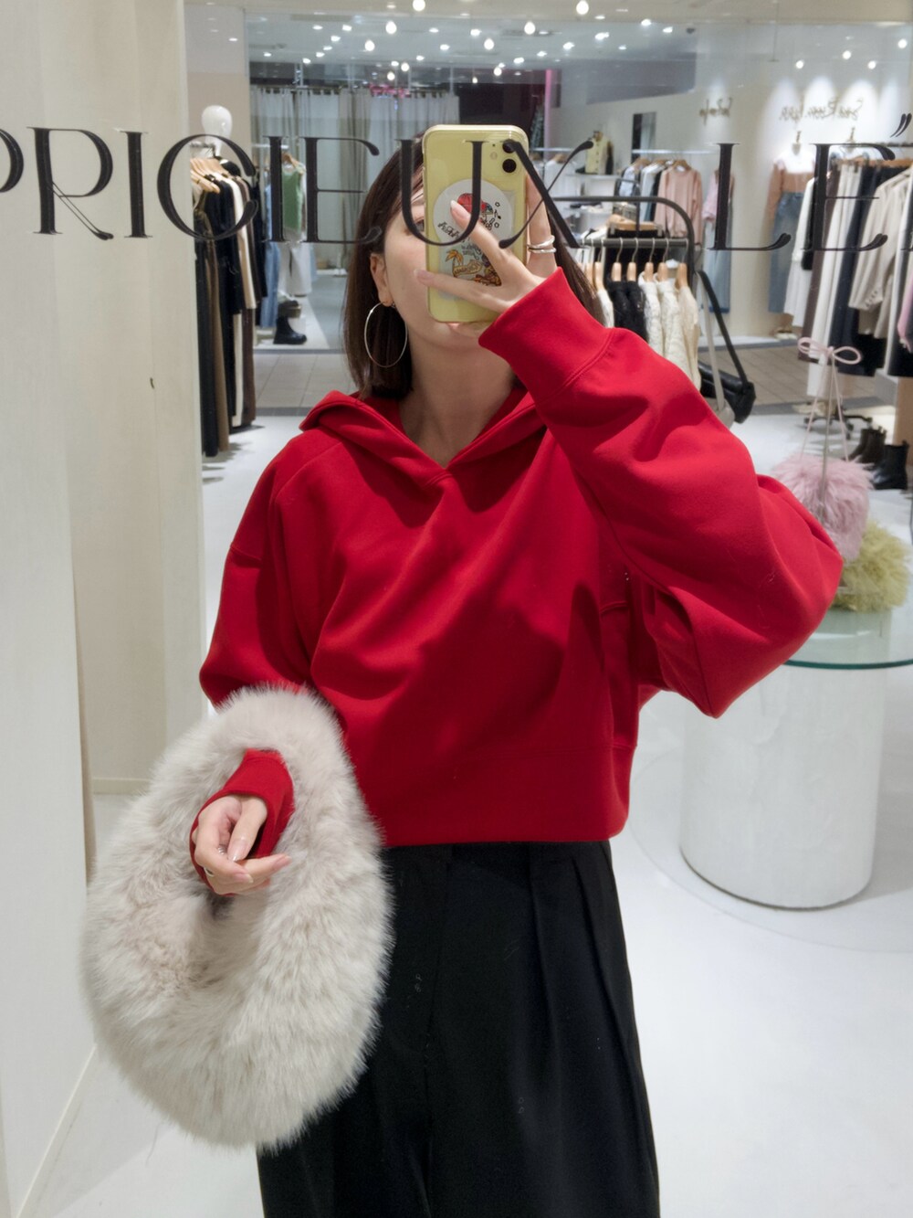 レッド系のパーカー、ホワイト系のハンドバッグ、ブラック系のその他パンツを着用したレディースの秋コーディネートの2枚目の写真