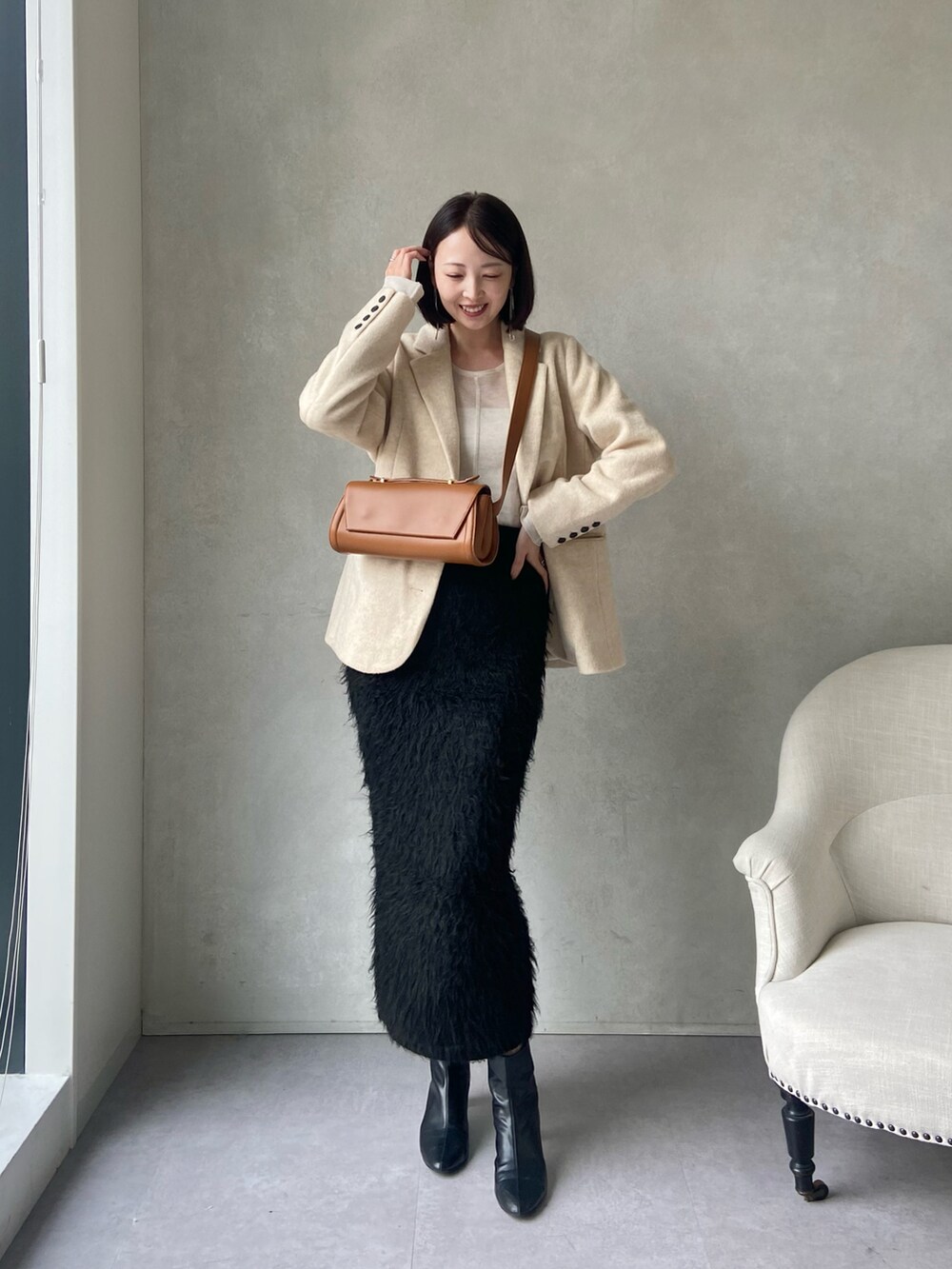 ベージュ系のテーラードジャケット、ブラック系のスカート、ベージュ系のショルダーバッグを着用したレディースの秋コーディネートの3枚目の写真