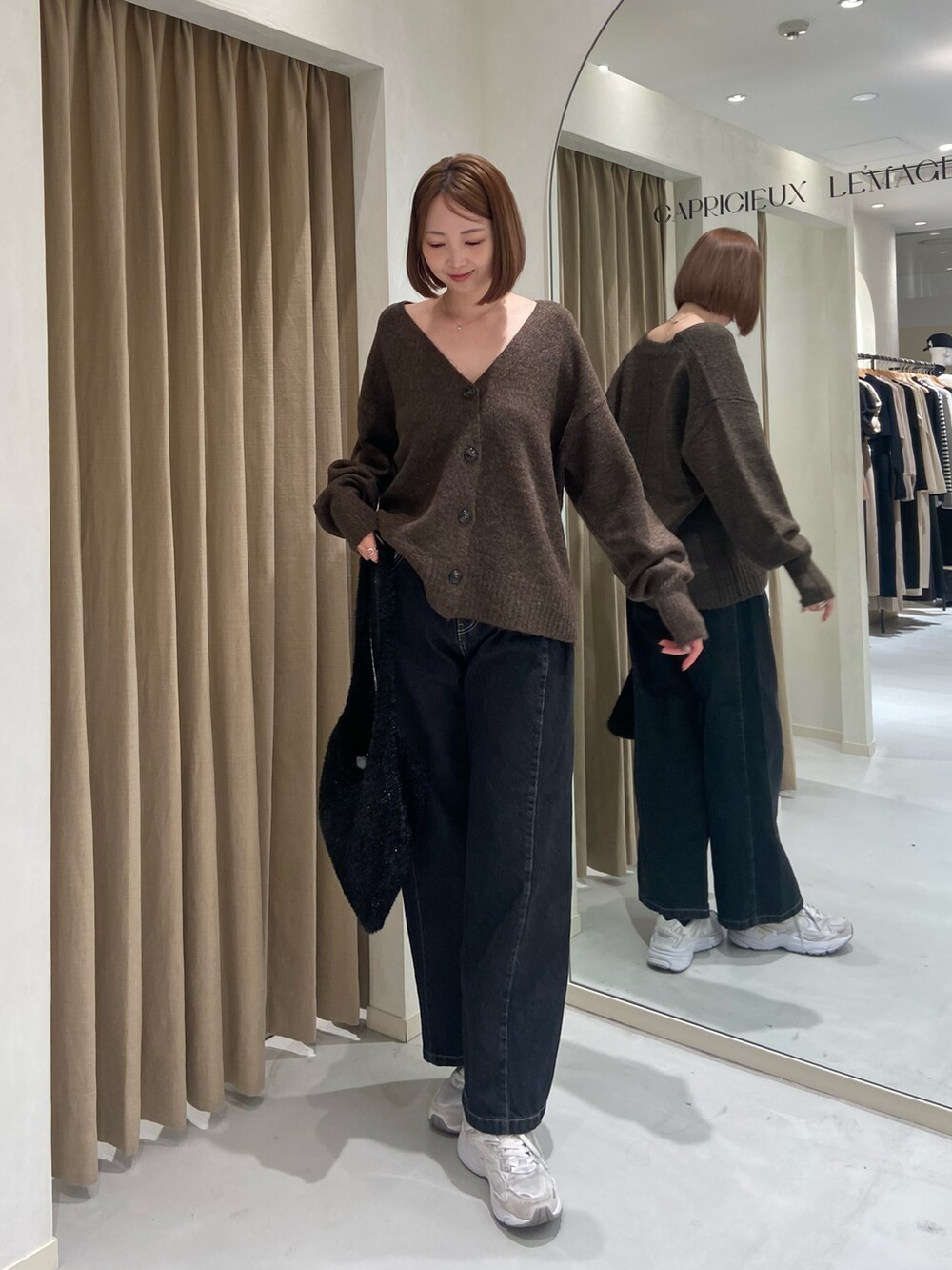 ブラウン系のカーディガン/ボレロ、ブラック系のデニムパンツ、ブラック系のショルダーバッグを着用したレディースの冬コーディネートの2枚目の写真