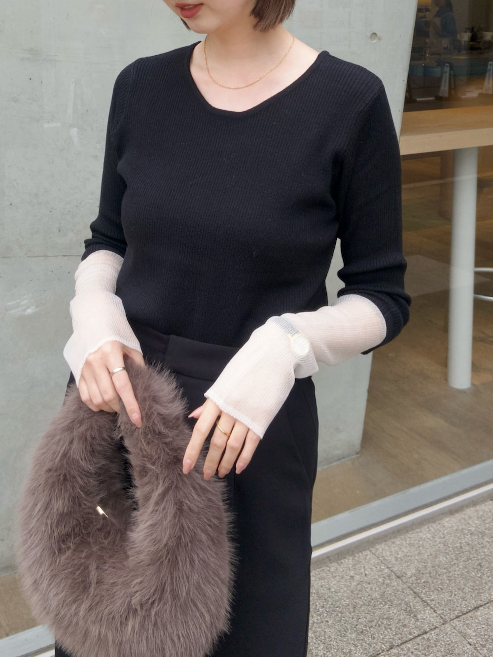 ブラック系のニット/セーター、ブラック系のスカート、ブラウン系のハンドバッグを着用したレディースの秋コーディネートの4枚目の写真