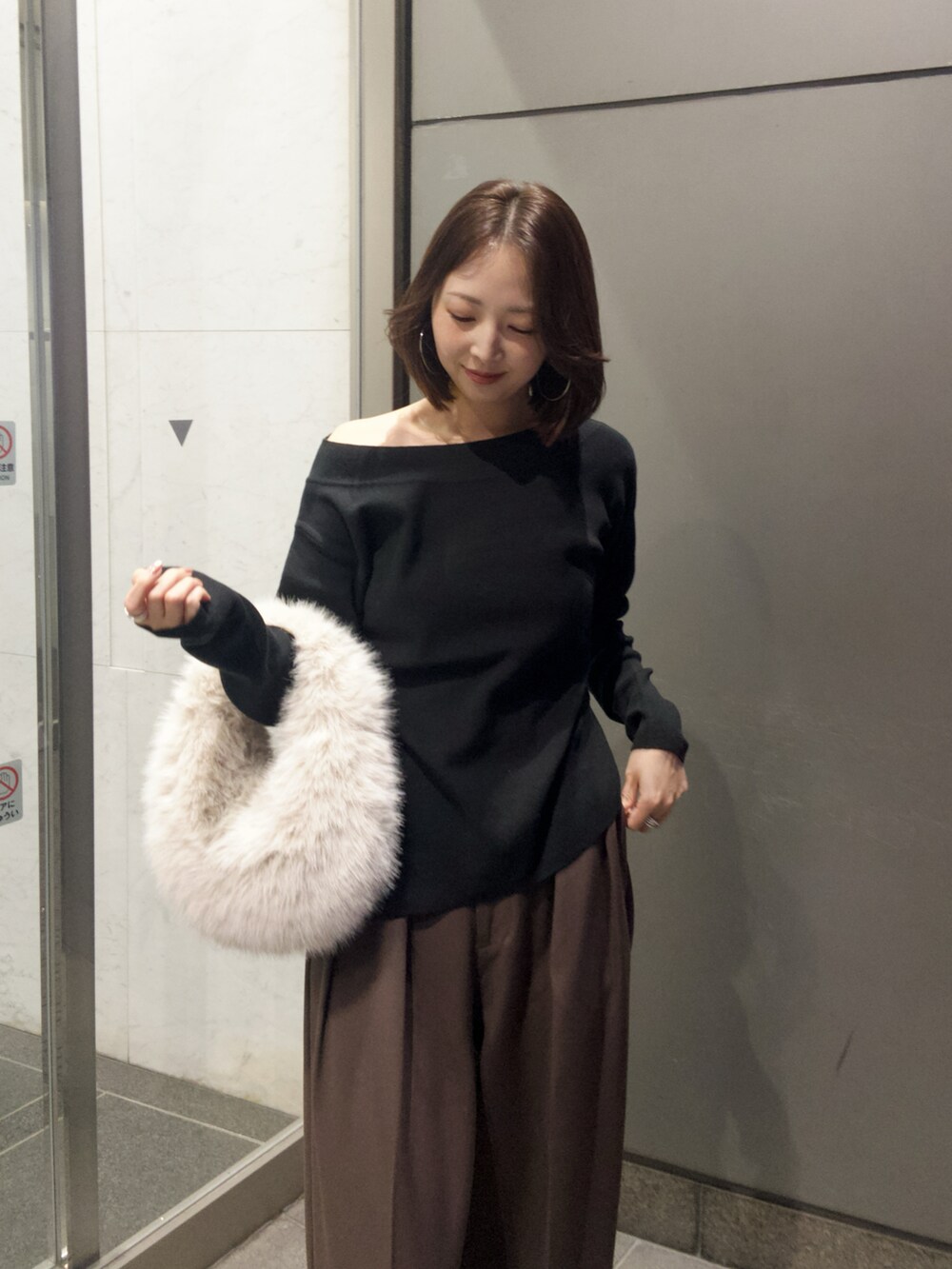 ブラック系のニット/セーター、ブラウン系のその他パンツ、ホワイト系のハンドバッグを着用したレディースの秋コーディネートの3枚目の写真
