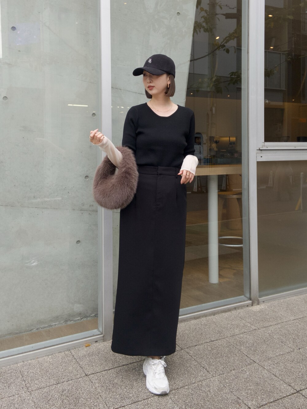 ブラック系のニット/セーター、ブラック系のスカート、ブラウン系のハンドバッグを着用したレディースの秋コーディネートの2枚目の写真
