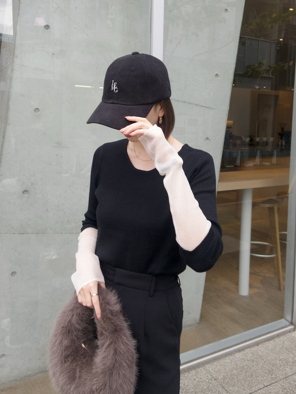 ブラック系のニット/セーター、ブラック系のスカート、ブラウン系のハンドバッグを着用したレディースの秋コーディネートの3枚目の写真