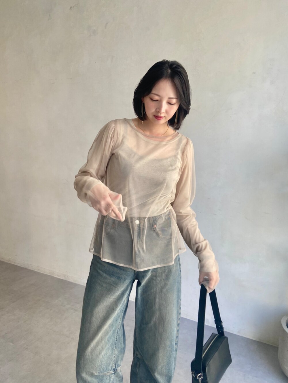 ブラック系のショルダーバッグ、ベージュ系のTシャツ/カットソーを着用したレディースの春コーディネートの2枚目の写真