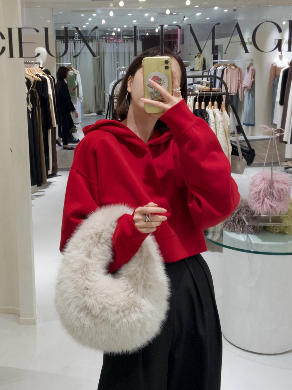 レッド系のパーカー、ホワイト系のハンドバッグ、ブラック系のその他パンツを着用したレディースの秋コーディネートの3枚目の写真