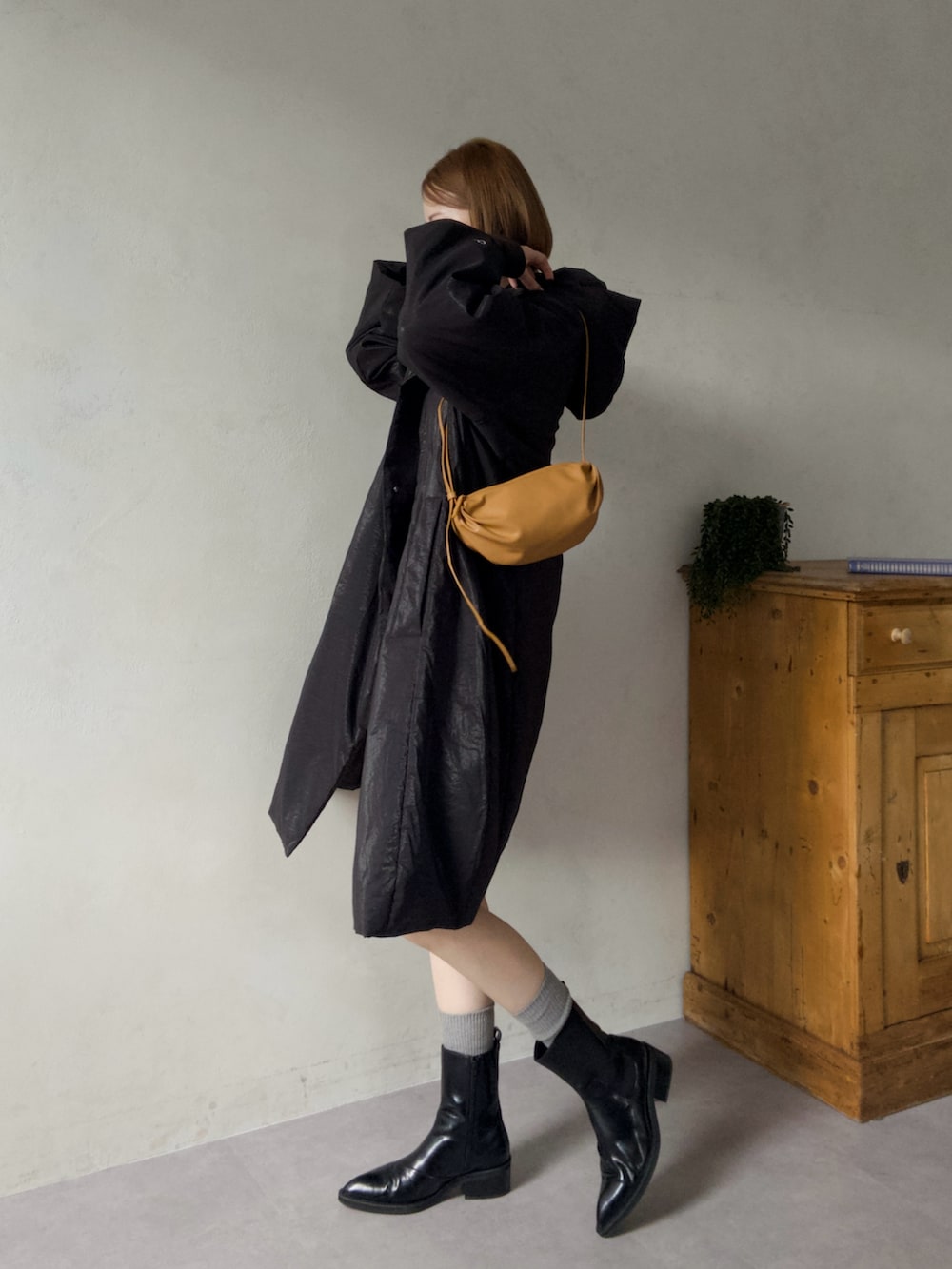 ブラック系のその他アウター、ブラック系のパンプス、イエロー系のショルダーバッグを着用したレディースの冬コーディネートの2枚目の写真