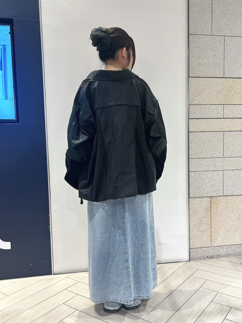 ブラック系のブルゾン、ブラック系のニット/セーター、ブルー系のデニムパンツを着用したレディースの夏コーディネートの2枚目の写真