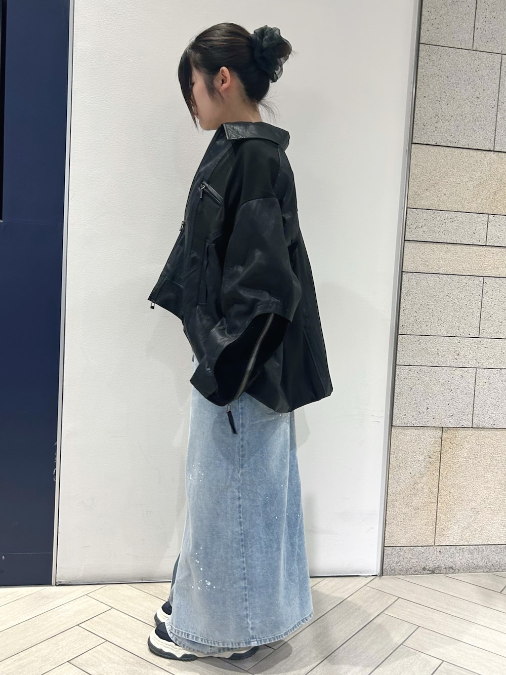 ブラック系のブルゾン、ブラック系のニット/セーター、ブルー系のデニムパンツを着用したレディースの夏コーディネートの3枚目の写真