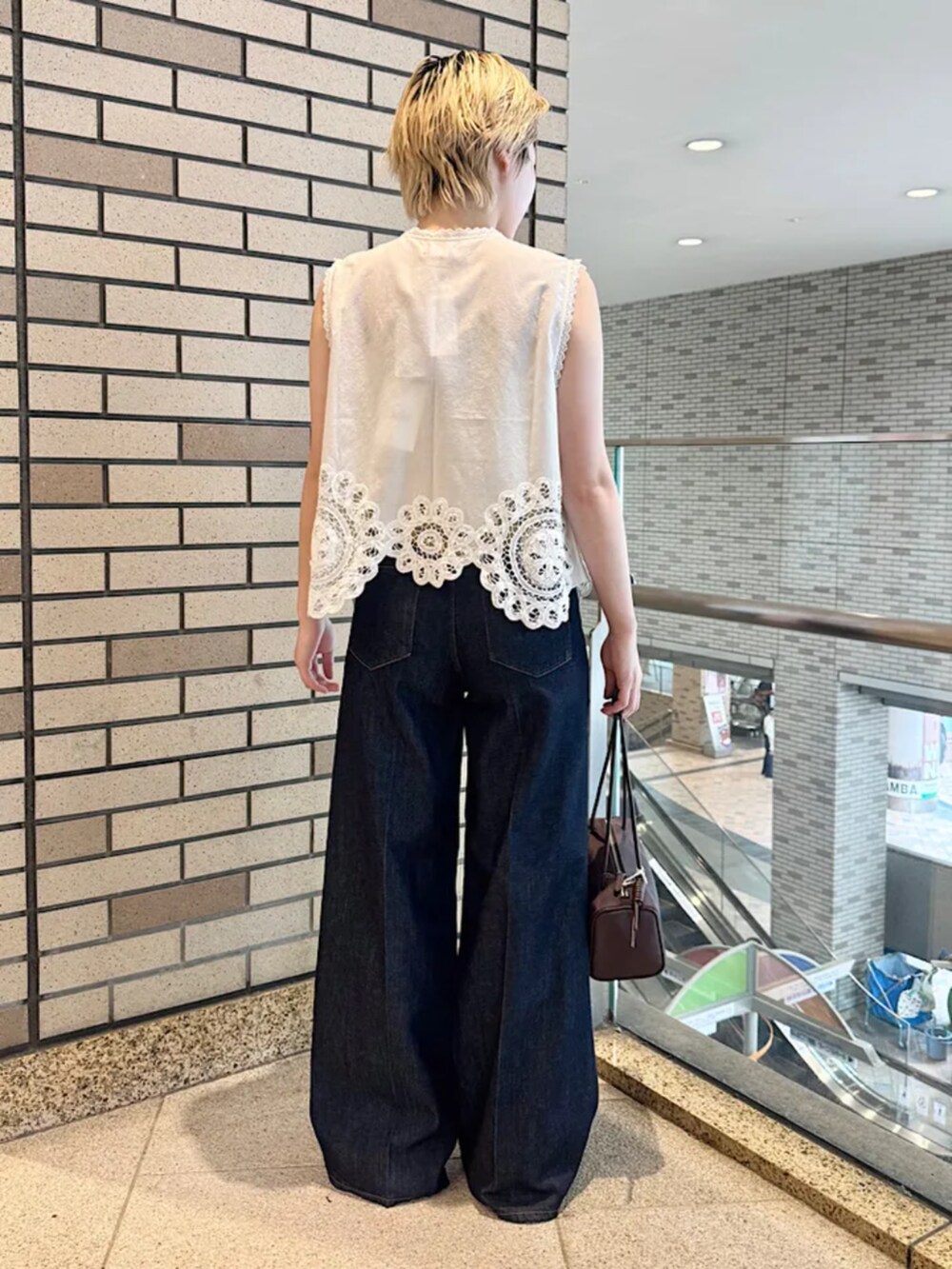 ブルー系のデニムパンツ、ブラウン系のショルダーバッグを着用したレディースの夏コーディネートの3枚目の写真