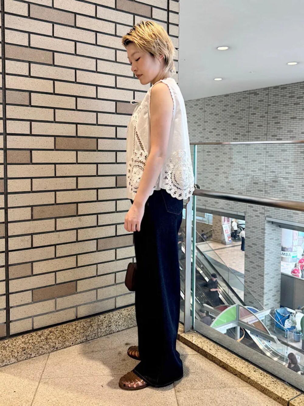 ブルー系のデニムパンツ、ブラウン系のショルダーバッグを着用したレディースの夏コーディネートの2枚目の写真