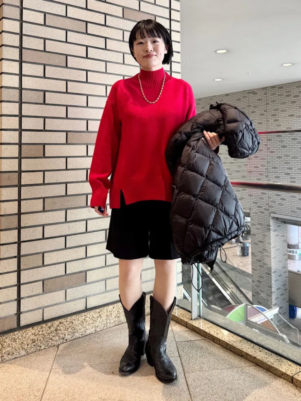 ブラック系のその他パンツ、ブラック系のダウンジャケット/コート、レッド系のニット/セーターを着用したレディースの冬コーディネートの2枚目の写真