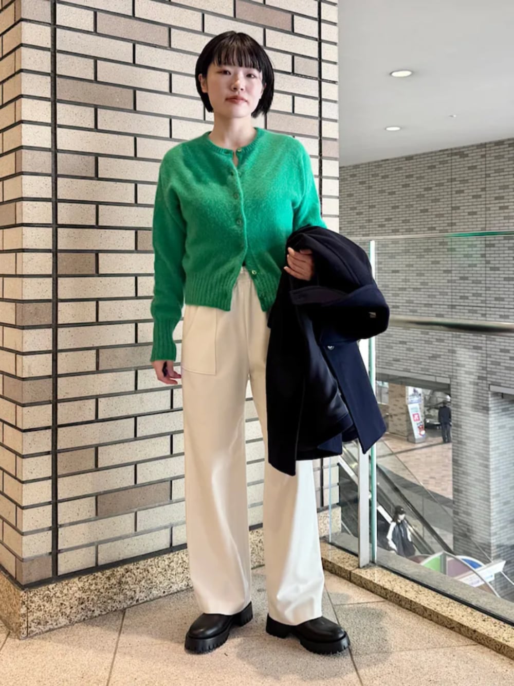 ブラック系のブーツ、ブラック系のショルダーバッグ、ブルー系のステンカラーコートを着用したレディースの冬コーディネートの3枚目の写真